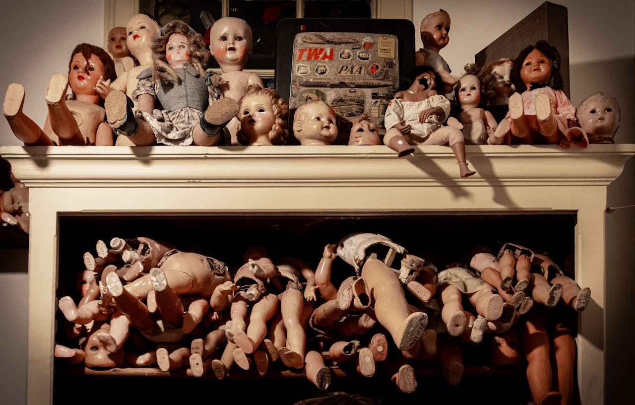 about-img-01 A spooky assortment of vintage dolls on a shelf, creating an eerie atmosphere.