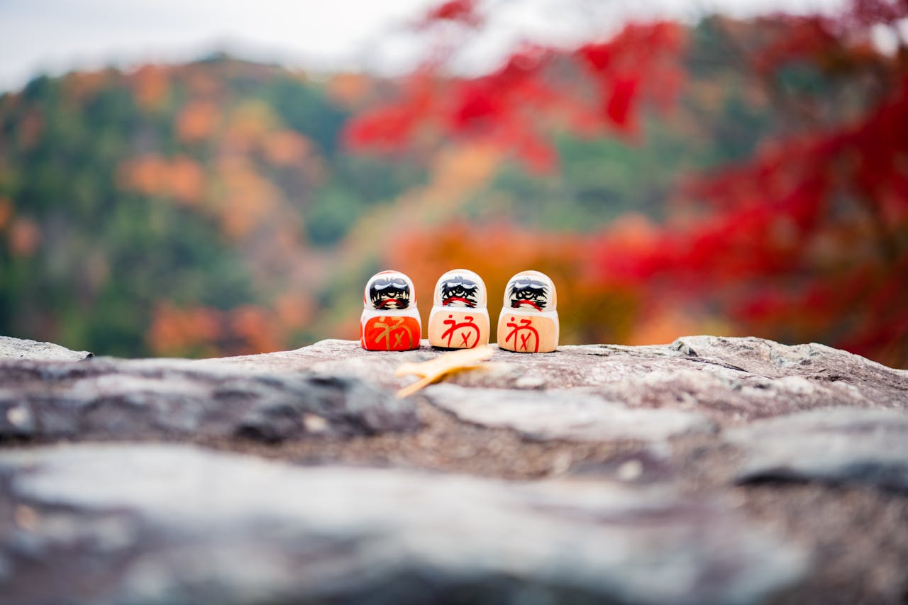 gallery-03 Colorful Daruma dolls set against autumn foliage in Minoo Park, Osaka, Japan.