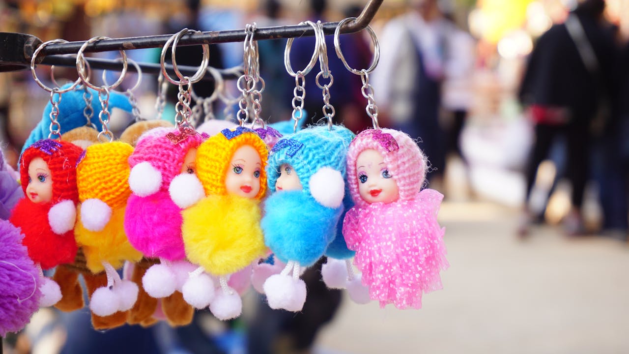 our-story Vibrant knitted doll keychains hanging on a rack, perfect for decorative purposes.