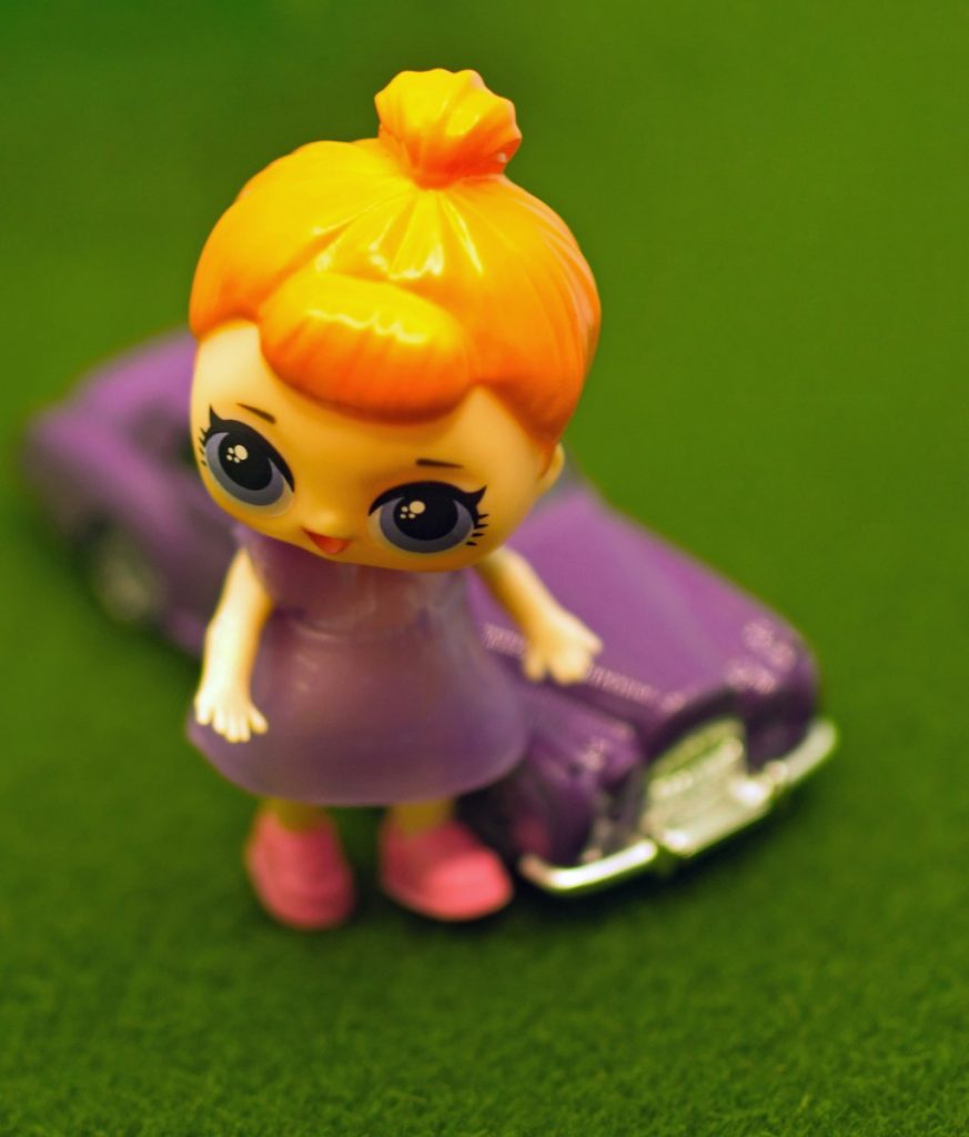 a little doll is sitting on top of a purple car