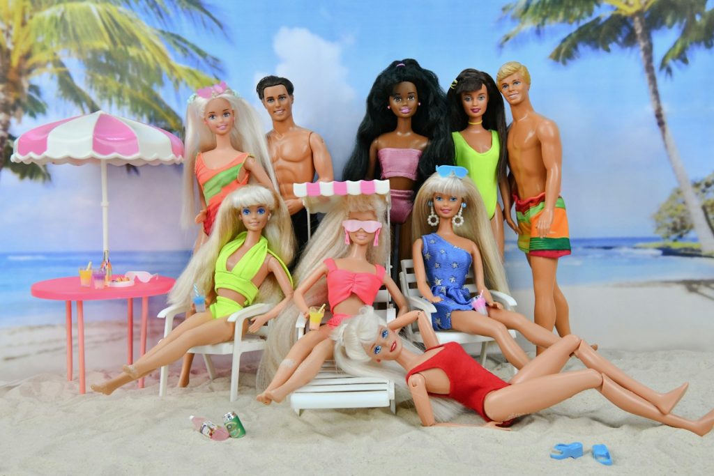 Group of dolls on a beach with umbrella and umbrella.